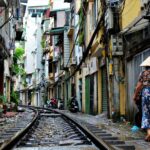 person walking on railway side between buildings at daytime