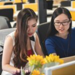 shallow focus photography of two women doing work in table