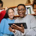 Man in Gray Sweater Holding Black Digital Table Smiling