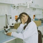 woman in white laboratory gown holding black microphone