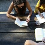 woman reading book while sitting on chair