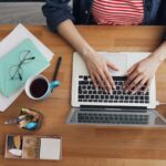 a woman sitting at a table working on a laptop