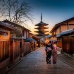 two women in purple and pink kimono standing on street