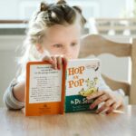 girl sitting while reading book