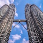 Low angle view of the iconic Petronas Twin Towers in Kuala Lumpur, Malaysia, against a clear blue sky.