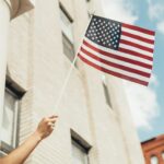 a person holding an american flag in front of a building