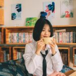 a woman sitting on a couch drinking a cup of coffee