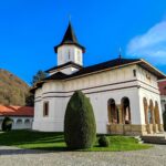 Beautiful Orthodox chapel surrounded by greenery in Transylvania with blue skies overhead.